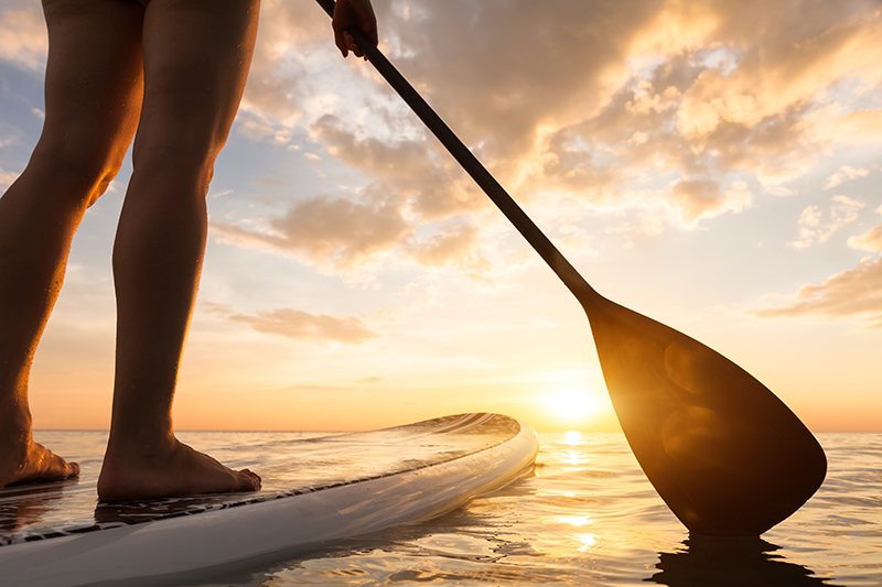 vacation person paddle boarding at sunset